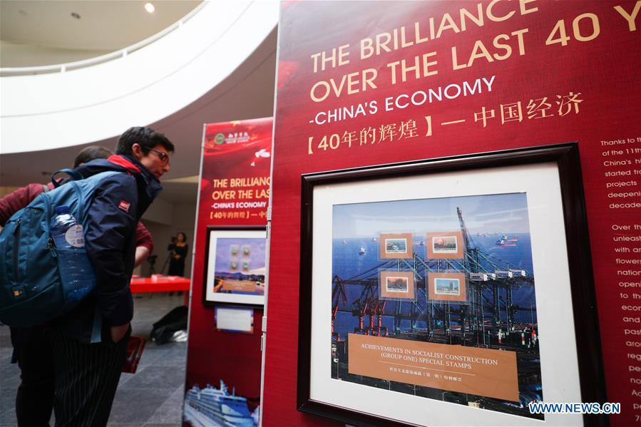 Visitors watch the stamps showing China\'s economic achievements during the \