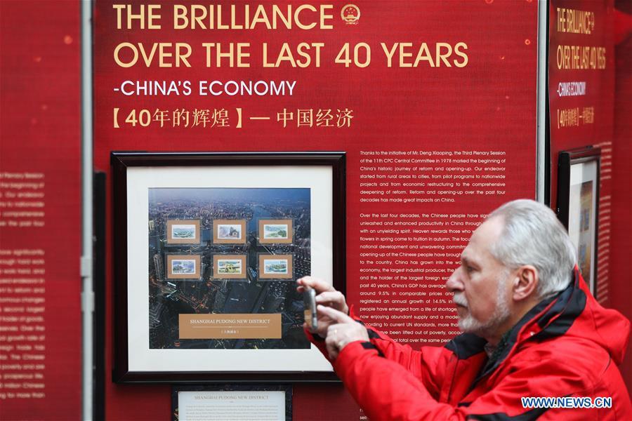 A visitor takes photos of the stamps showing China\'s economic achievements during the \