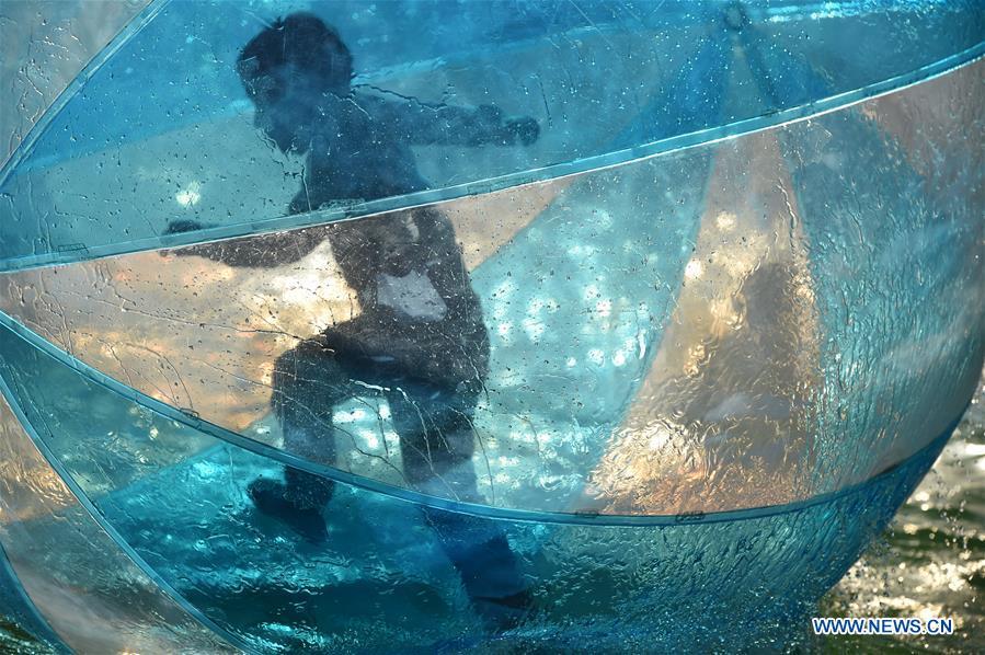 A kid enjoys himself in a huge balloon on the water at Xinghua Park in Hefei, capital of east China\'s Anhui Province, Dec. 16, 2018. Balmy weather in winter in Hefei recently helped promote outdoor recreation. (Xinhua/Yang Xiaoyuan)