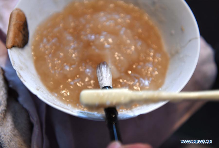 A worker applies glue as making the Xuan ink brush at a workshop in Huangcun Town of Jingxian County, east China\'s Anhui Province, Dec. 14, 2018. Huangcun Town has a long history of the Xuan ink brush making. The ink brush, ink, Chinese Xuan paper and ink slabs are four traditional writing materials of Chinese stationery. (Xinhua/Liu Junxi)
