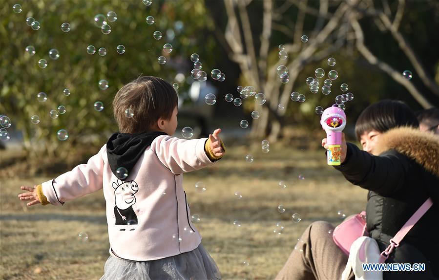 A kid plays with soap bubbles at Xinghua Park in Hefei, capital of east China\'s Anhui Province, Dec. 16, 2018. Balmy weather in winter in Hefei recently helped promote outdoor recreation. (Xinhua/Yang Xiaoyuan)