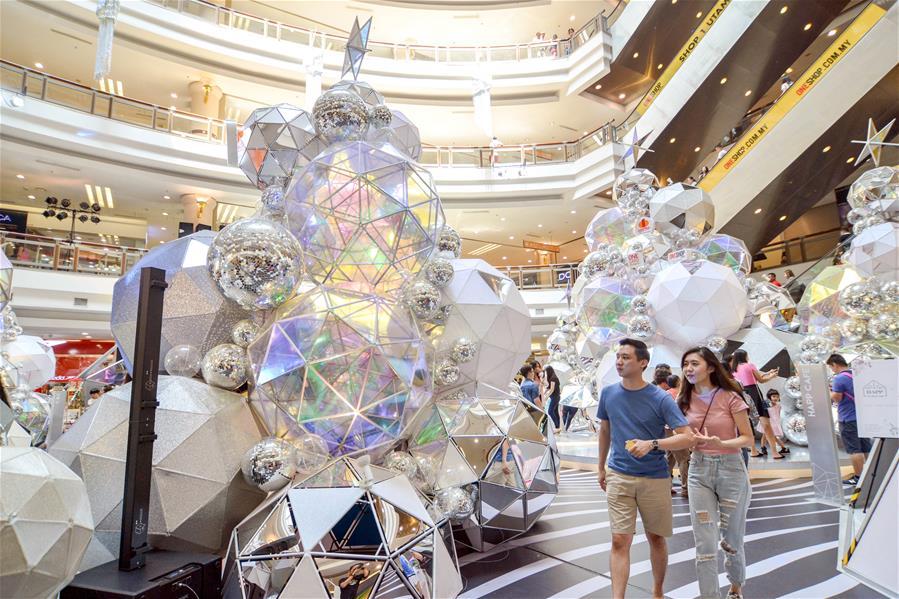 Customers walk past decorations set up for the upcoming Christmas season at a shopping mall in Kuala Lumpur, Malaysia, on Dec. 16, 2018. (Xinhua/Chong Voon Chung)
