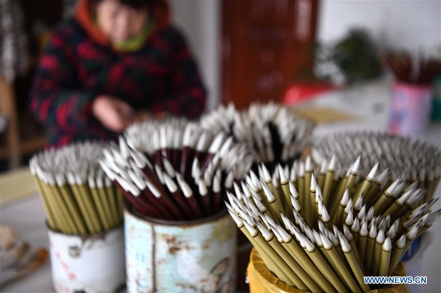 A worker sticks the trademarks on the Xuan ink brushes at a workshop in Huangcun Town of Jingxian County, east China\'s Anhui Province, Dec. 14, 2018. Huangcun Town has a long history of the Xuan ink brush making. The ink brush, ink, Chinese Xuan paper and ink slabs are four traditional writing materials of Chinese stationery. (Xinhua/Liu Junxi)