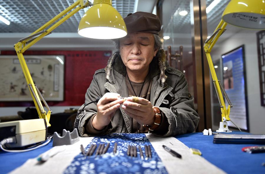 Han Zhiyao creates a nut carving work at his studio in Dalian, Liaoning Province, on Dec。 12. （Photo/Xinhua）