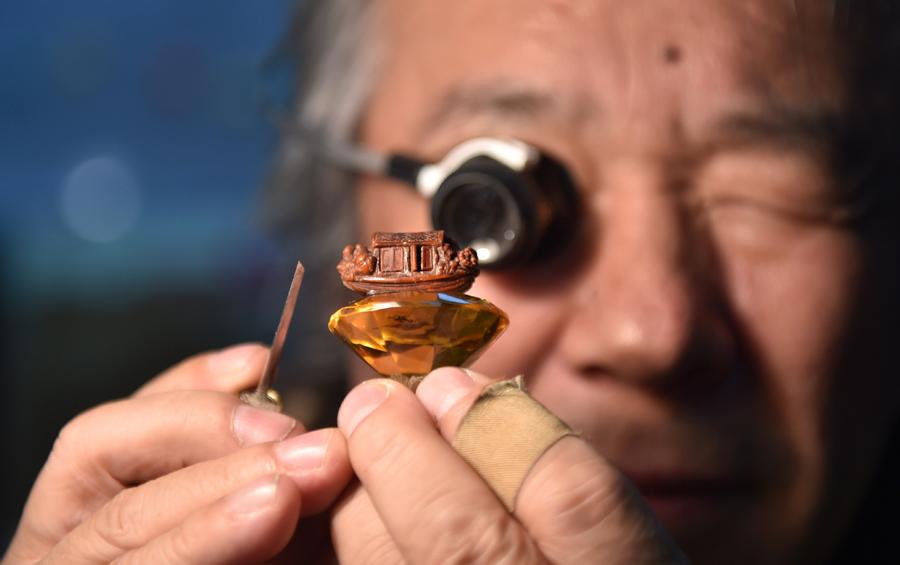 Han Zhiyao cleans up his work The Nut-carving Boat at his studio in Dalian, Liaoning Province, on Dec. 12, which reproduce the nut carving work recorded in the article The Nut-carving Boat in the Ming Dynasty (1368-1644). (Photo/Xinhua)

Dalian nut carving, which involves turning the cores of walnuts into artworks, is an ancient folk art based on traditional meticulous sculpture. It was listed as one of China\'s national intangible cultural heritage in 2014.

Han Zhiyao, 62-year-old inheritor of Dalian nut carving, has learned the skill since childhood. Familiar folk stories and historical allusions are reproduced in the small nuts through his skillful hands.

In recent years, Han Zhiyao has been trying to incorporate more traditional cultural elements into nut carving. He hopes to create more works in his lifetime so that this skill can reach the world.