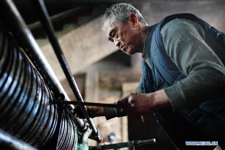 Yang Qiqing, a 68-year-old villager, adjusts the steel to extract camellia oil, also known as tea seed oil, in Licha Village of Longsheng County, south China\'s Guangxi Zhuang Autonomous Region, Dec. 17, 2018. Camellia oil made with traditional methods by workshops in the village is quite popular in market because of its better quality and longer guarantee. (Xinhua/Huang Yongdan)