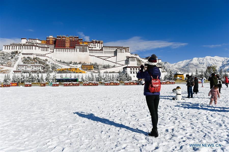 A tourist takes photos at the snow-covered Potala Palace square in Lhasa, capital of southwest China\'s Tibet Autonomous Region, Dec. 19, 2018. Lhasa witnessed the first snow this winter on Tuesday. (Xinhua/Liu Dongjun)