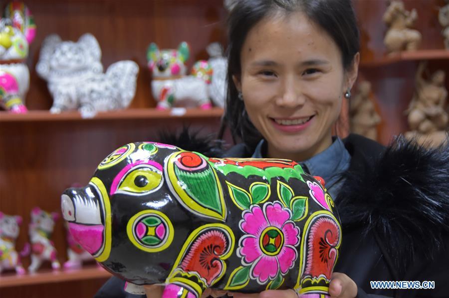 A clay sculpture artist shows a clay pig sculpture in Liuying Village of Fengxiang County, northwest China\'s Shaanxi Province, Dec. 20, 2018. Artists of Liuying Village of Fengxiang County, known as the hometown of clay sculpture, were busy making clay sculptures to greet the upcoming Chinese lunar new year, the Year of the Pig. (Xinhua/Du Honggang)