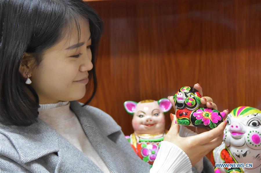A visitor looks at a clay pig sculpture in Liuying Village of Fengxiang County, northwest China\'s Shaanxi Province, Dec. 20, 2018. Artists of Liuying Village of Fengxiang County, known as the hometown of clay sculpture, were busy making clay sculptures to greet the upcoming Chinese lunar new year, the Year of the Pig. (Xinhua/Du Honggang)
