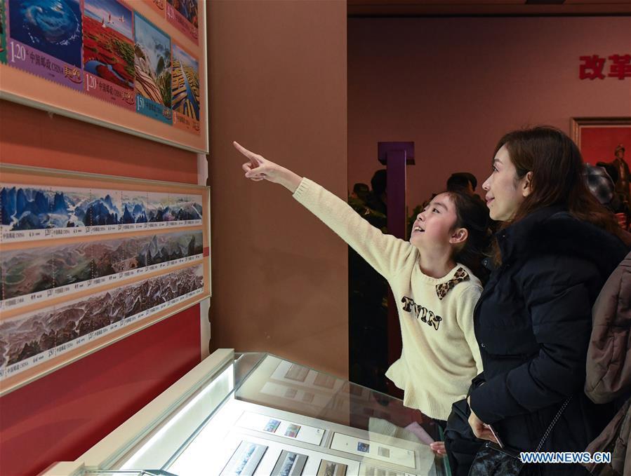 People look at the stamps displayed during a major exhibition to commemorate the 40th anniversary of China\'s reform and opening-up at the National Museum of China in Beijing, capital of China, Dec. 22, 2018. The exhibition has received more than 1.85 million visitors since its opening. (Xinhua/Li He)