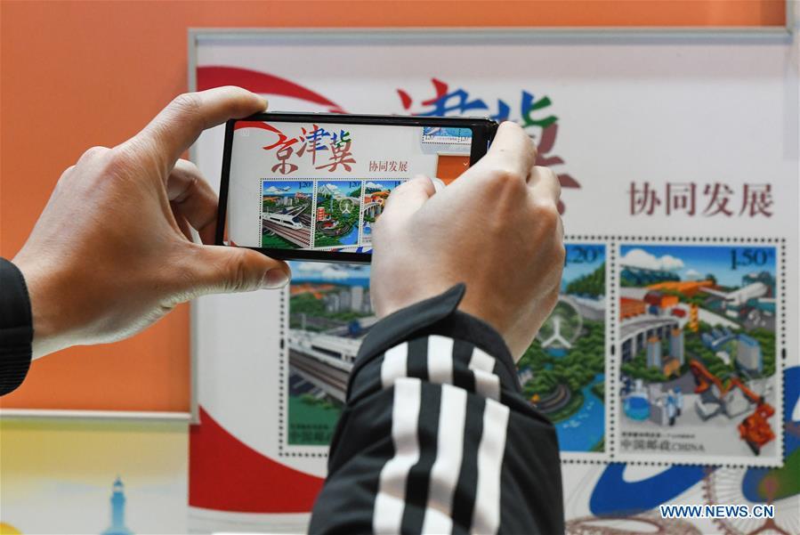 A visitor takes photos of the stamps displayed during a major exhibition to commemorate the 40th anniversary of China\'s reform and opening-up at the National Museum of China in Beijing, capital of China, Dec. 22, 2018. The exhibition has received more than 1.85 million visitors since its opening. (Xinhua/Li He)