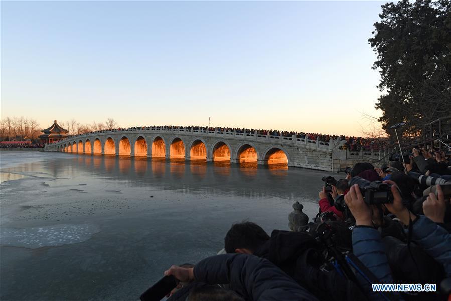 Visitors and photographers take photos of the Qikong Bridge with sunset glow shining through its holes at the Summer Palace in Beijing, capital of China, Dec, 23, 2018. (Xinhua/Chen Yehua)