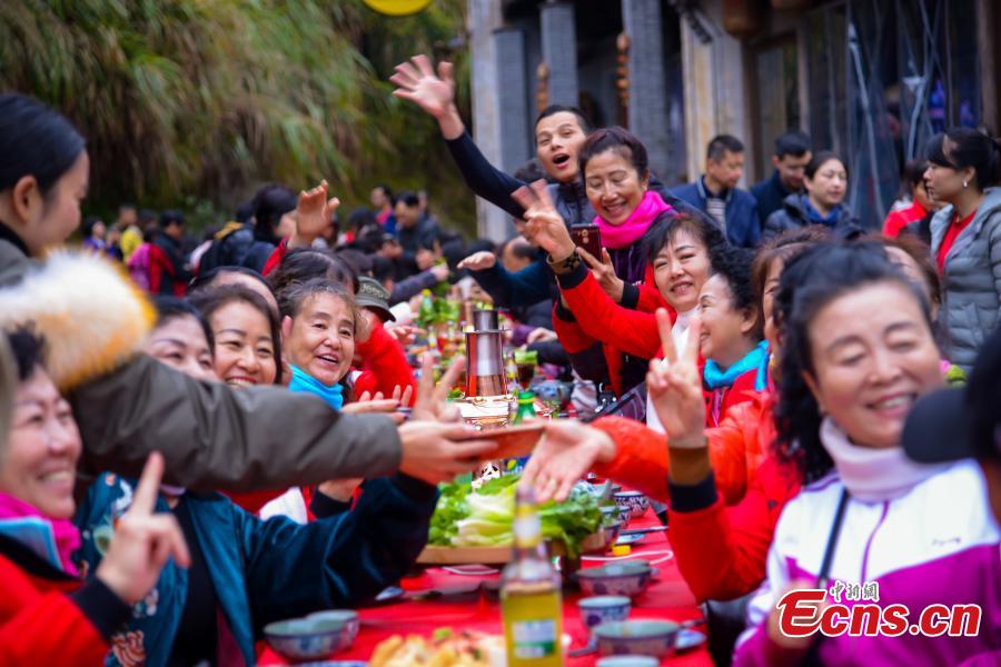 A hot-pot banquet is held on a street in Huangling Ancient Village in Wuyuan County, East China\'s Jiangxi Province, Dec. 22, 2018. The centerpiece of the long-table banquet, a traditional manner in which to celebrate some major festivals and entertain guests, is a giant copper pot measuring three meters in height and two meters in diameter. Visitors, including some from Singapore and Malaysia, joined the feast, where the tables extended for 100 meters. (Photo: China News Service/Fang Huabin)