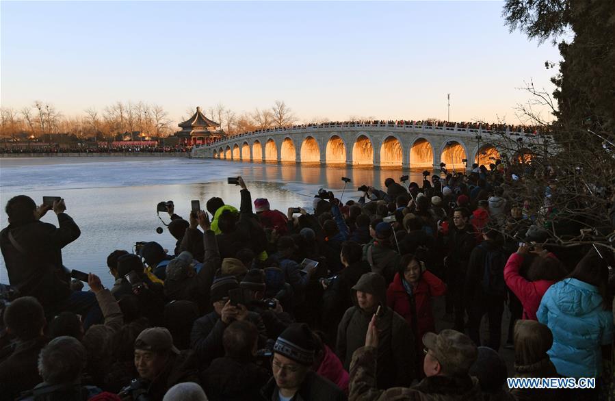 Visitors and photographers take photos of the Qikong Bridge with sunset glow shining through its holes at the Summer Palace in Beijing, capital of China, Dec, 23, 2018. (Xinhua/Chen Yehua)