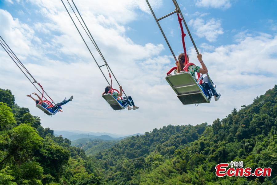 Photo shows three people up in the sky in the chair of a cliff swing that opened to the public in Qingyuan, Guangdong Province on December 19, 2018. The swing above a 198-meter waterfall on Mount Tianzi in Qingyuan, South China\'s Guangdong Province officially opens on Thursday after a four-month trial operation.  (Photo: China News Service/Cheng Jingwei)