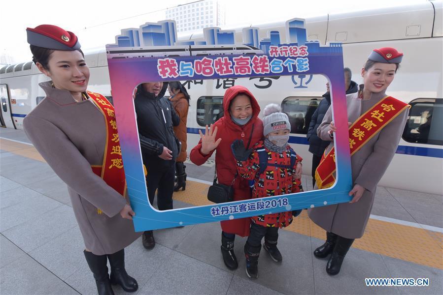 Passengers pose for photos with the bullet train at the Mudanjiang Railway Station in Mudanjiang, northeast China\'s Heilongjiang Province, Dec. 25, 2018. A high-speed railway line officially went into operation on Tuesday, linking cities of Harbin and Mudanjiang in China\'s northernmost province of Heilongjiang, where the temperatures dip as low as minus 40 degrees Celsius. (Xinhua/Zhang Chunxiang)