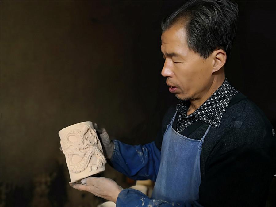 Liu Quan shows one of his works. (Photo by Wei Jianjun for chinadaily.com.cn)
