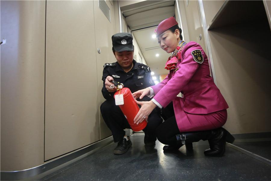 Liu Yuting and a security worker inspect a fire extinguisher on the train.  (Photo provided to chinadaily.com.cn)