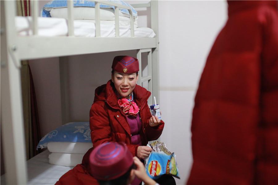 After a day\'s work, like many other young women, Liu enjoys light moments chatting with her colleagues while eating snacks at her dormitory in Shijiazhuang, Hebei province. Liu said she is proud to be a high-speed train attendant after going through a strict selection process. But she admitted that she has little time to spend with her family and hopes to reunite with them on the train she serves during the upcoming Spring Festival holiday. (Photo provided to chinadaily.com.cn)