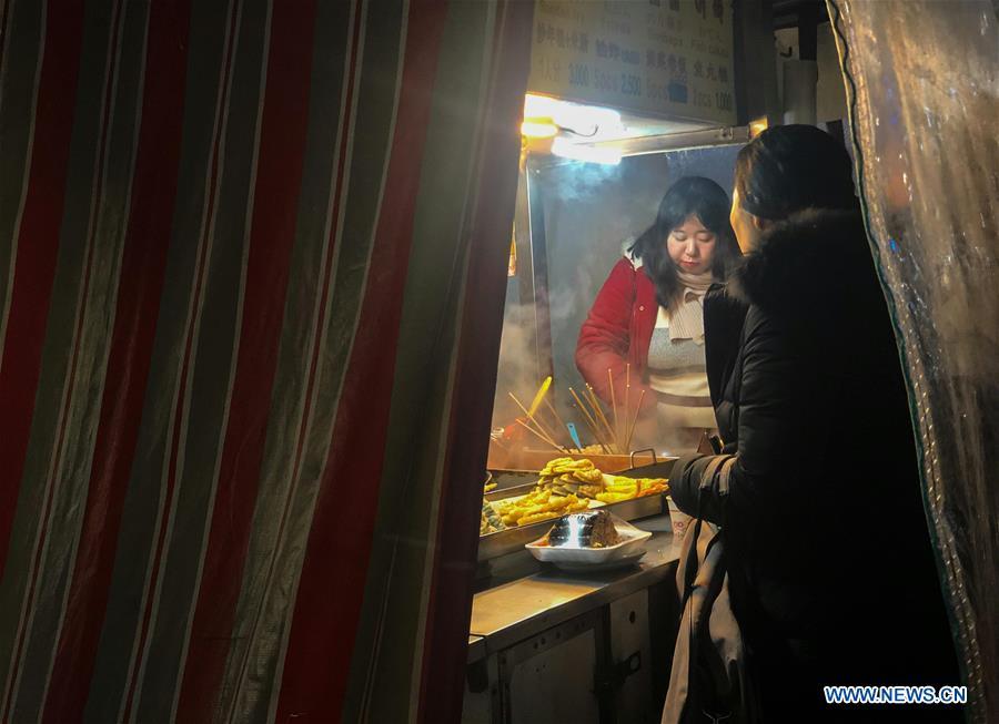 People enjoy hot food at a stall in Seoul, South Korea, Dec. 28, 2018. A cold wave hit the country on Friday, dipping Seoul\'s temperature to minus 19.3 degrees Celsius. (Xinhua/Wang Jingqiang)