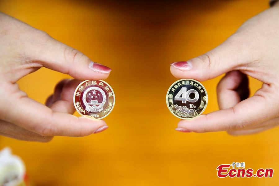 Photo taken on Dec. 28, 2018 shows banknotes and coins to commemorate the 70th anniversary of the establishment of the People\'s Bank of China and the 40th anniversary of the reform and opening-up respectively go on sale in Taiyuan City, North China\'s Shanxi Province. The 50-yuan commemorative banknote is 150 millimeters long and 70 millimeters wide, the same size as the regular 50-yuan banknote in the country\'s fifth set of notes. (Photo: China News Service/Zhang Yun)