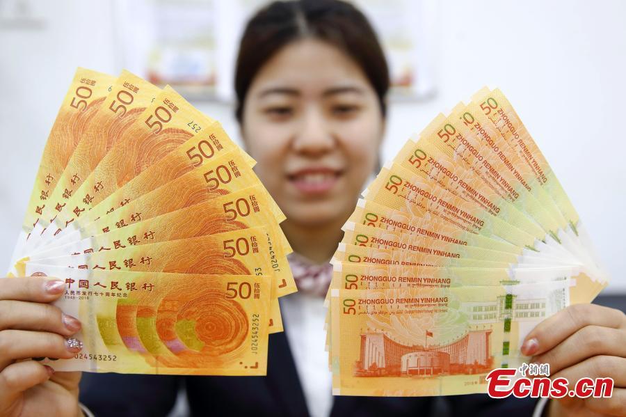 Photo taken on Dec. 28, 2018 shows banknotes and coins to commemorate the 70th anniversary of the establishment of the People\'s Bank of China and the 40th anniversary of the reform and opening-up respectively go on sale in Taiyuan City, North China\'s Shanxi Province. The 50-yuan commemorative banknote is 150 millimeters long and 70 millimeters wide, the same size as the regular 50-yuan banknote in the country\'s fifth set of notes. (Photo: China News Service/Zhang Yun)