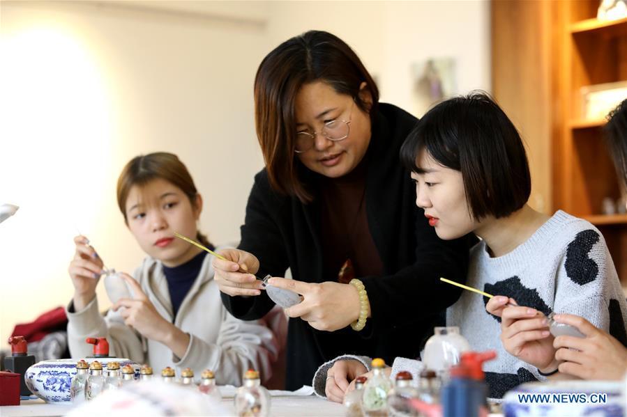Yin Jianqing (C) teaches students inner painting technique at Hebei College of Industry and Technology in Shijiazhuang, north China\'s Hebei Province, Dec. 28, 2018. The college takes intangible cultural heritages such as techniques of pyrograph and inner painting into school courses in recent years. (Xinhua/Liang Zidong)