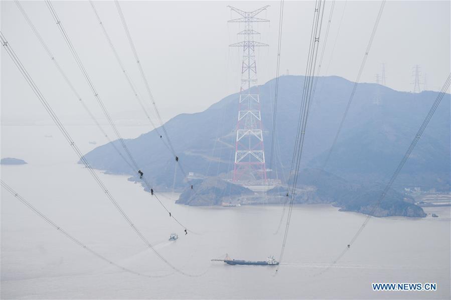 Staff members work on the cables at the site of the giant power supply pylons in Zhoushan, east China\'s Zhejiang Province, Jan. 3, 2019. The two 380-meter-tall pylons carry power cables between Zhoushan\'s Jintang and Cezi islands, a distance of 2,656 meters. The new pylon project is a part of a new ultra-high voltage power line project between cities of Zhoushan and Ningbo. (Xinhua/Xu Yu)