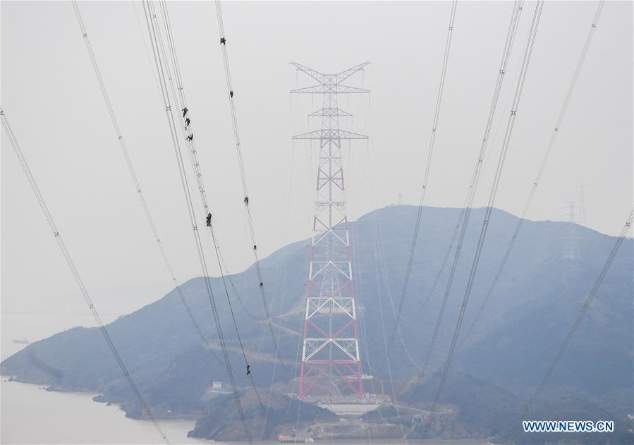 Staff members work on the cables at the site of the giant power supply pylons in Zhoushan, east China\'s Zhejiang Province, Jan. 3, 2019. The two 380-meter-tall pylons carry power cables between Zhoushan\'s Jintang and Cezi islands, a distance of 2,656 meters. The new pylon project is a part of a new ultra-high voltage power line project between cities of Zhoushan and Ningbo. (Xinhua/Xu Yu)