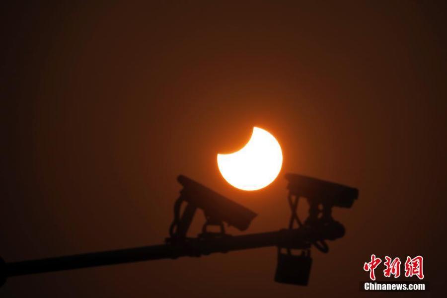 A partial solar eclipse is observed next to security cameras in Jingshan Park in Beijing, Jan. 6, 2019. (Photo: China News Service/Sun Zifa)