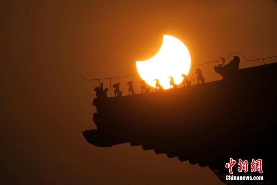 A partial solar eclipse is observed next to the Forbidden City in Beijing, Jan. 6, 2019. (Photo: China News Service/Sun Zifa)