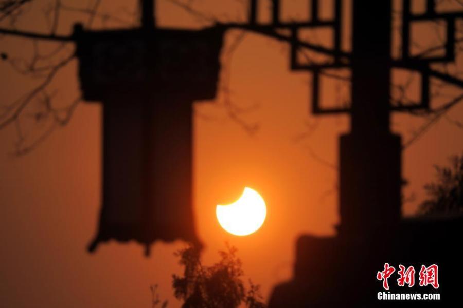 A partial solar eclipse is observed next to lanterns in Jingshan Park in Beijing, Jan. 6, 2019. (Photo: China News Service/Sun Zifa)