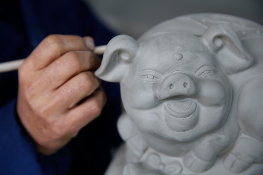 Wang Guoqi works on the base of a Ru porcelain ware shaped like a pig at his studio in Central China\'s Henan Province on Jan. 7, 2019. (Photo/Asianewsphoto)