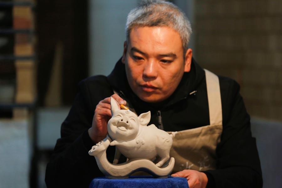 A man works on the base of a Ru porcelain ware shaped like a pig at Wang Guoqi\'s studio in Central China\'s Henan Province on Jan. 7, 2019. (Photo/Asianewsphoto)