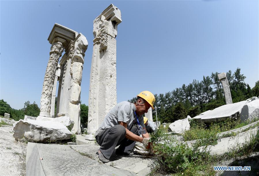 Staff members clean up weeds at ruins of Yuanying Guan (Immense Ocean Observatory) at Yuanmingyuan in Beijing, capital of China, May 23, 2018. The National Cultural Heritage Administration will work out a plan to better protect cultural relics and speed up the creation of a safety oversight platform in 2019. Stressing the importance of such protection, Liu Yuzhu, head of the administration, said lax enforcement is a prominent problem that endangers cultural relics, at a meeting attended by cultural heritage administrators nationwide. (Xinhua/Luo Xiaoguang)