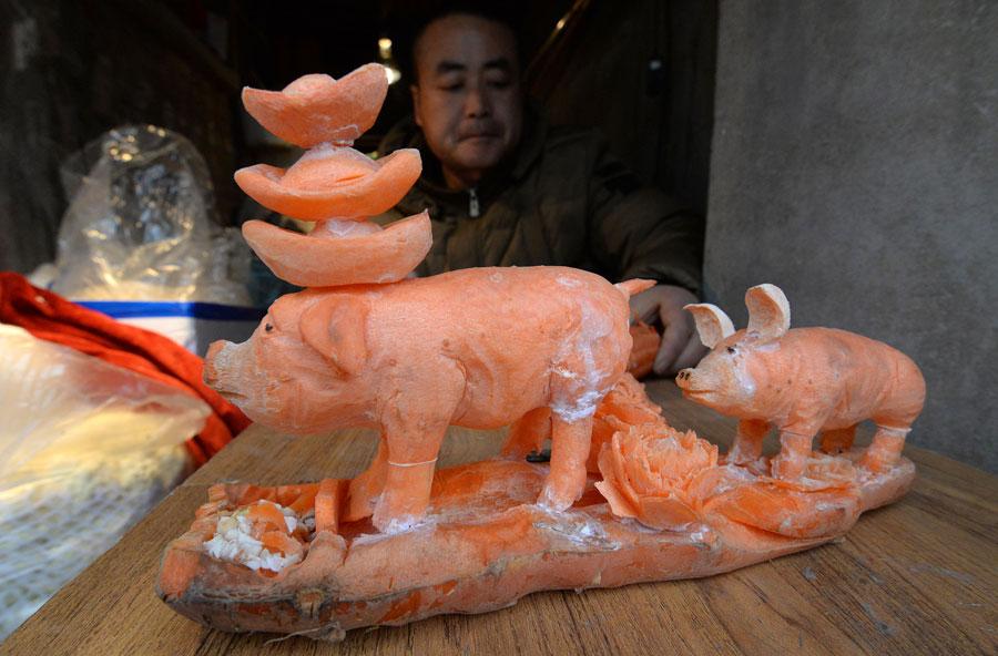 A sculpture of pigs carved out of carrots by Guo Yuhong, a vegetable vendor at a market in Handan, North China\'s Hebei Province.  (Photo by Hao Qunying for chinadaily.com.cn)