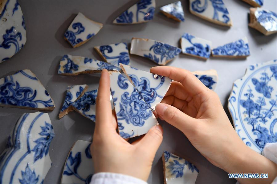 A porcelain restorer matches fragments of an ancient porcelain of Ming Dynasty in Jingdezhen, east China\'s Jiangxi Province, on Oct. 18, 2018. The National Cultural Heritage Administration will work out a plan to better protect cultural relics and speed up the creation of a safety oversight platform in 2019. Stressing the importance of such protection, Liu Yuzhu, head of the administration, said lax enforcement is a prominent problem that endangers cultural relics, at a meeting attended by cultural heritage administrators nationwide. (Xinhua/Wan Xiang)
