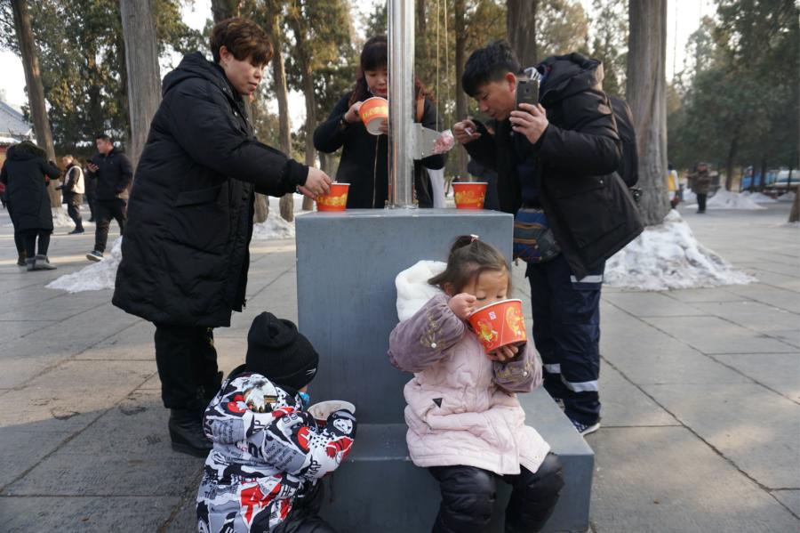 Visitors share Laba congee handed out for free during an event taking place in front of the temple\'s Shaolin Medicine health unit, Jan. 13, 2019. The congee was cooked according to a traditional recipe and included five types of beans as well as more than 20 minor ingredients. Buddhist temples across China have started handing out free Laba congee, a special meal served during the Laba Festival, which falls on the eighth day of the 12th lunar month and ushers in China\'s Lunar New Year celebrations. (Photo: China News Service/Han Zhangyun)