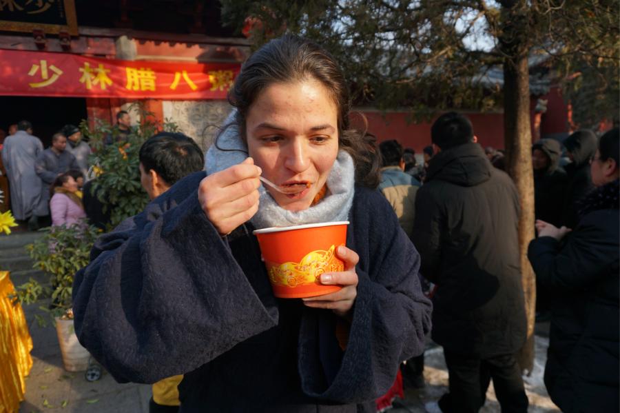 Visitors share Laba congee handed out for free during an event taking place in front of the temple\'s Shaolin Medicine health unit, Jan. 13, 2019. The congee was cooked according to a traditional recipe and included five types of beans as well as more than 20 minor ingredients. Buddhist temples across China have started handing out free Laba congee, a special meal served during the Laba Festival, which falls on the eighth day of the 12th lunar month and ushers in China\'s Lunar New Year celebrations. (Photo: China News Service/Han Zhangyun)