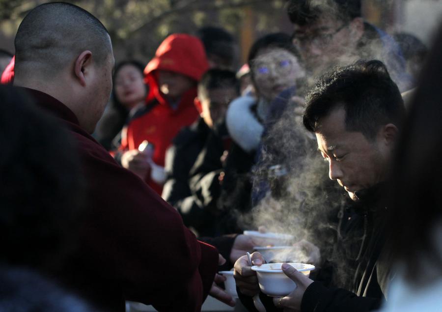 Visitors and tourists taste Laba porridge at Yonghe Temple, Beijing, on Jan. 13, 2019.  (Photo/China Daily)