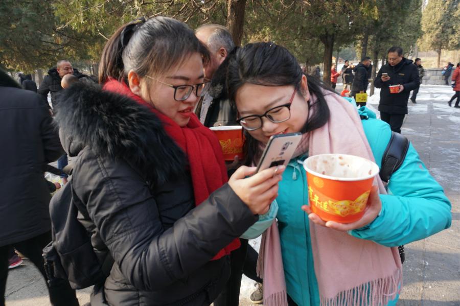 Visitors share Laba congee handed out for free during an event taking place in front of the temple\'s Shaolin Medicine health unit, Jan. 13, 2019. The congee was cooked according to a traditional recipe and included five types of beans as well as more than 20 minor ingredients. Buddhist temples across China have started handing out free Laba congee, a special meal served during the Laba Festival, which falls on the eighth day of the 12th lunar month and ushers in China\'s Lunar New Year celebrations. (Photo: China News Service/Han Zhangyun)