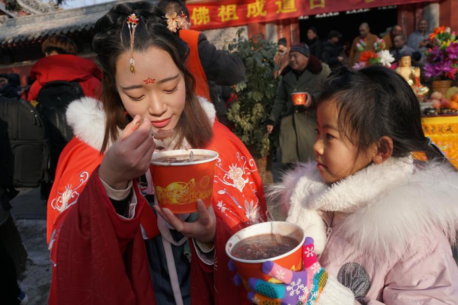 Visitors share Laba congee handed out for free during an event taking place in front of the temple\'s Shaolin Medicine health unit, Jan. 13, 2019. The congee was cooked according to a traditional recipe and included five types of beans as well as more than 20 minor ingredients. Buddhist temples across China have started handing out free Laba congee, a special meal served during the Laba Festival, which falls on the eighth day of the 12th lunar month and ushers in China\'s Lunar New Year celebrations. (Photo: China News Service/Han Zhangyun)