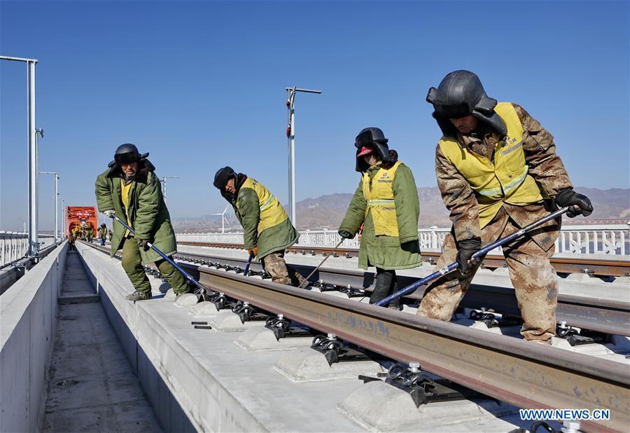 Workers lay the tracks for the Beijing-Zhangjiakou high-speed railway line at Guanting Reservoir grand bridge in north China\'s Hebei Province, on Jan. 13, 2019. Track laying work of the Beijing-Zhangjiakou high-speed railway line at Guanting Reservoir grand bridge was completed on Sunday. The 174-km-long railway, connecting China\'s capital Beijing and Zhangjiakou of north China\'s Hebei Province, is a major transportation project for the 2022 Winter Olympic Games. (Xinhua/Yang Shiyao)
