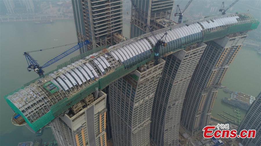Core construction work on a 300-meter-long conservatory, part of the Raffles City Chongqing complex, is complete in Southwest China\'s Chongqing, Jan. 14, 2019. Located at the confluence of the Yangtze and Jialing rivers, Raffles City Chongqing has been designed by world-renown architect Moshe Safdie, who drew inspiration from the region\'s thousand years of waterway transportation history. The conservatory, 32.5 meters wide and 26.5 meters tall, connects the tops of four buildings, 250 meters above the ground, as well as accommodating a viewing deck, an infinity pool, a sky walk and varied dining options. (Photo provided to China News Service)