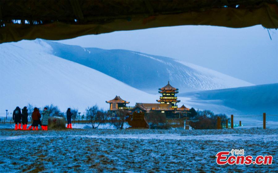The Crescent Spring and Singing-Sand Dunes scenic spot in Dunhuang City, Northwest China\'s Gansu Province, after its first snow of the year, Jan. 19, 2019. Riding a camel across the desert landscape has become a popular activity for tourists to the area. (Photo: China News Service/Wang Binyin)