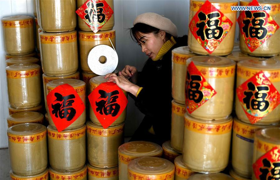 A worker pastes Chinese character Fu, or blessings in English, on Shuizhagou preserved meat pots at a factory in Pingshan County, north China\'s Hebei Province, Jan. 22, 2019. Shuizhagou preserved meat, a local speciality famous for its delicate taste and fine making method, is a treat for families and friends on important occasions. (Xinhua/Chen Qibao)
