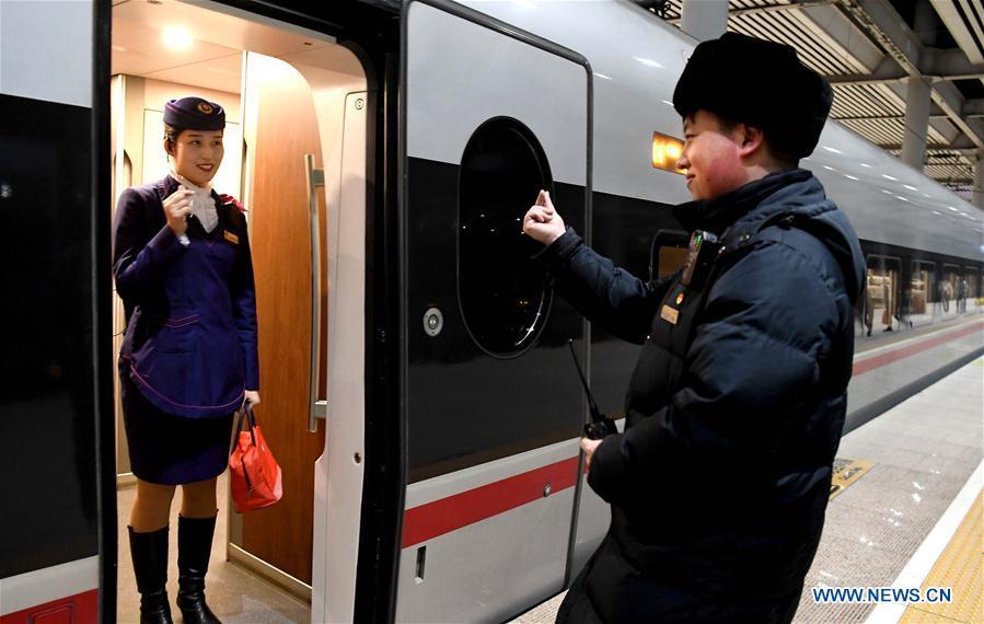 Li Xiang and his wife, Zou Xiaojuan, pose a gesture symbolizing \'love\' to each other before the departure of the train No. G402 at Xinxiangdong Railway Station in Xinxiang City, central China\'s Henan Province, Jan. 22, 2019. Li Xiang is a staff worker of Xinxiangdong Railway Station and his wife Zou Xiaojuan is a train conductor on the train No. G402. The two-minute stop of the train No. G402 at Xinxiangdong Railway Station is their precious quality time in the bustle during the Spring Festival travel rush. (Xinhua/Li An)