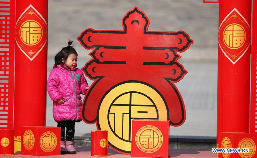 A girl is attracted by a lunar New Year decoration in Tancheng County of Linyi City, east China\'s Shandong Province, Jan. 24, 2019. Festive decorations are set up across China to greet the lunar New Year, or Spring Festival, which starts from Feb. 5 this year. (Xinhua/Zhang Chunlei)