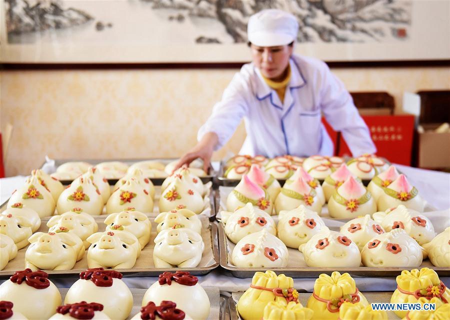 A villager takes buns off a shelf, which are made to celebrate the lunar New Year in Shengjiazhuang Village, Jiaozhou City of east China\'s Shandong Province, Jan. 24, 2019. (Xinhua/Wang Zhaomai)