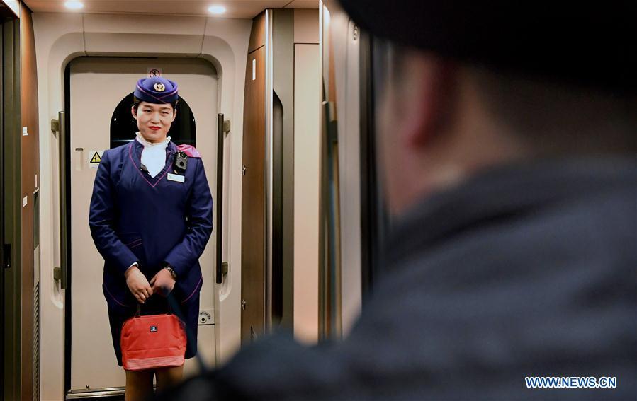 After receiving the lunch box, Li Xiang\'s wife, Zou Xiaojuan, smiles at Li during a temporary stop of the train No. G402 at Xinxiangdong Railway Station in Xinxiang City, central China\'s Henan Province, Jan. 22, 2019. Li Xiang is a staff worker of Xinxiangdong Railway Station and his wife Zou Xiaojuan is a train conductor on the train No. G402. The two-minute stop of the train No. G402 at Xinxiangdong Railway Station is their precious quality time in the bustle during the Spring Festival travel rush. (Xinhua/Li An)